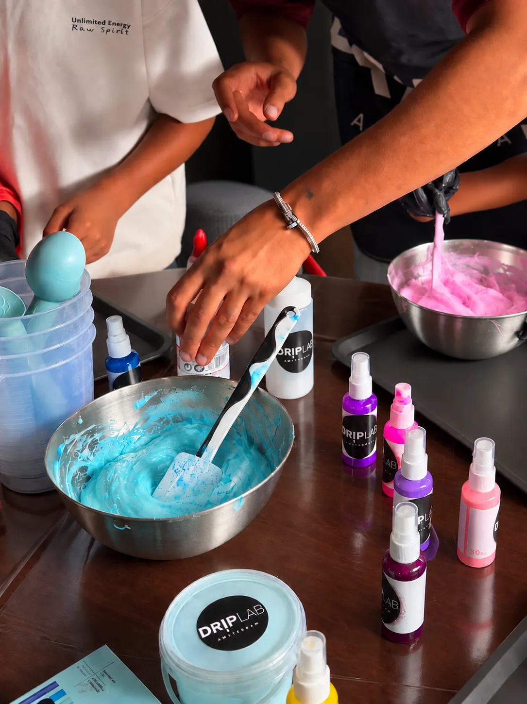 Kinderen mengen blauwe en roze slijm met DRIPLAB-kleurflesjes tijdens een workshop