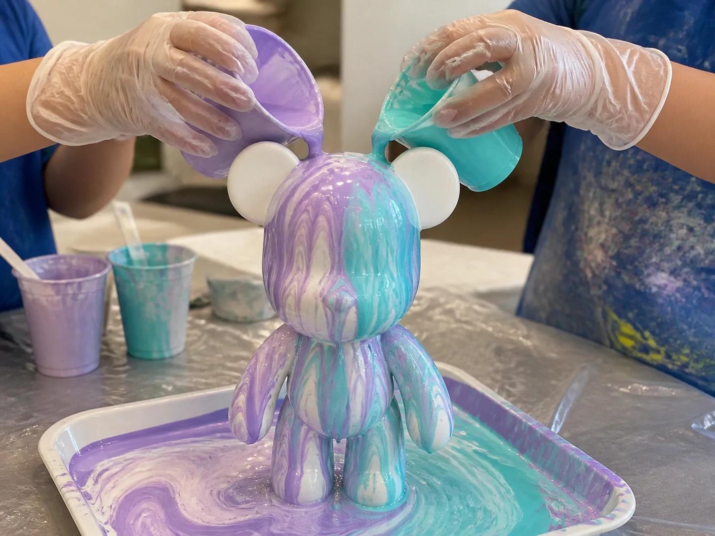 Kinderhanden die paarse en blauwe verf over een witte art bear gieten