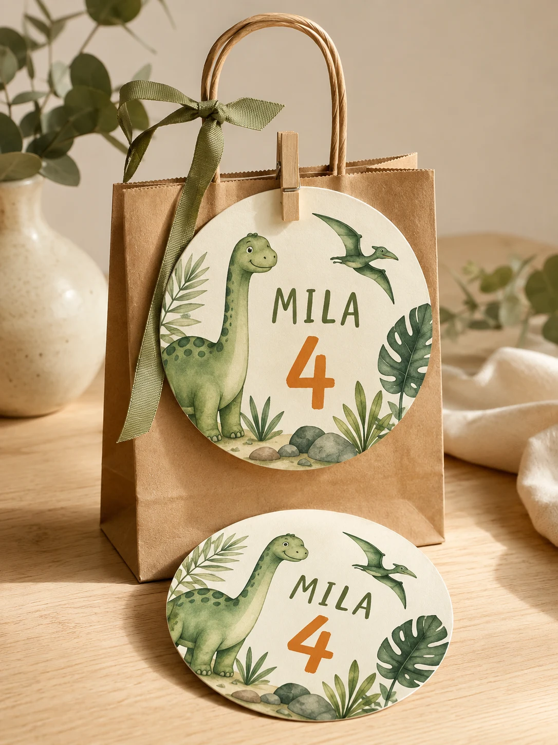 Ronde dinobadge met Mila en het cijfer 4 aan een kraft feesttasje